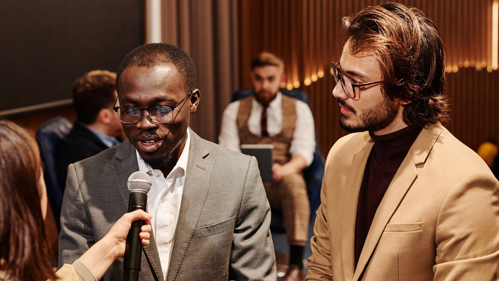 A man answering a question into a microphone while another listens