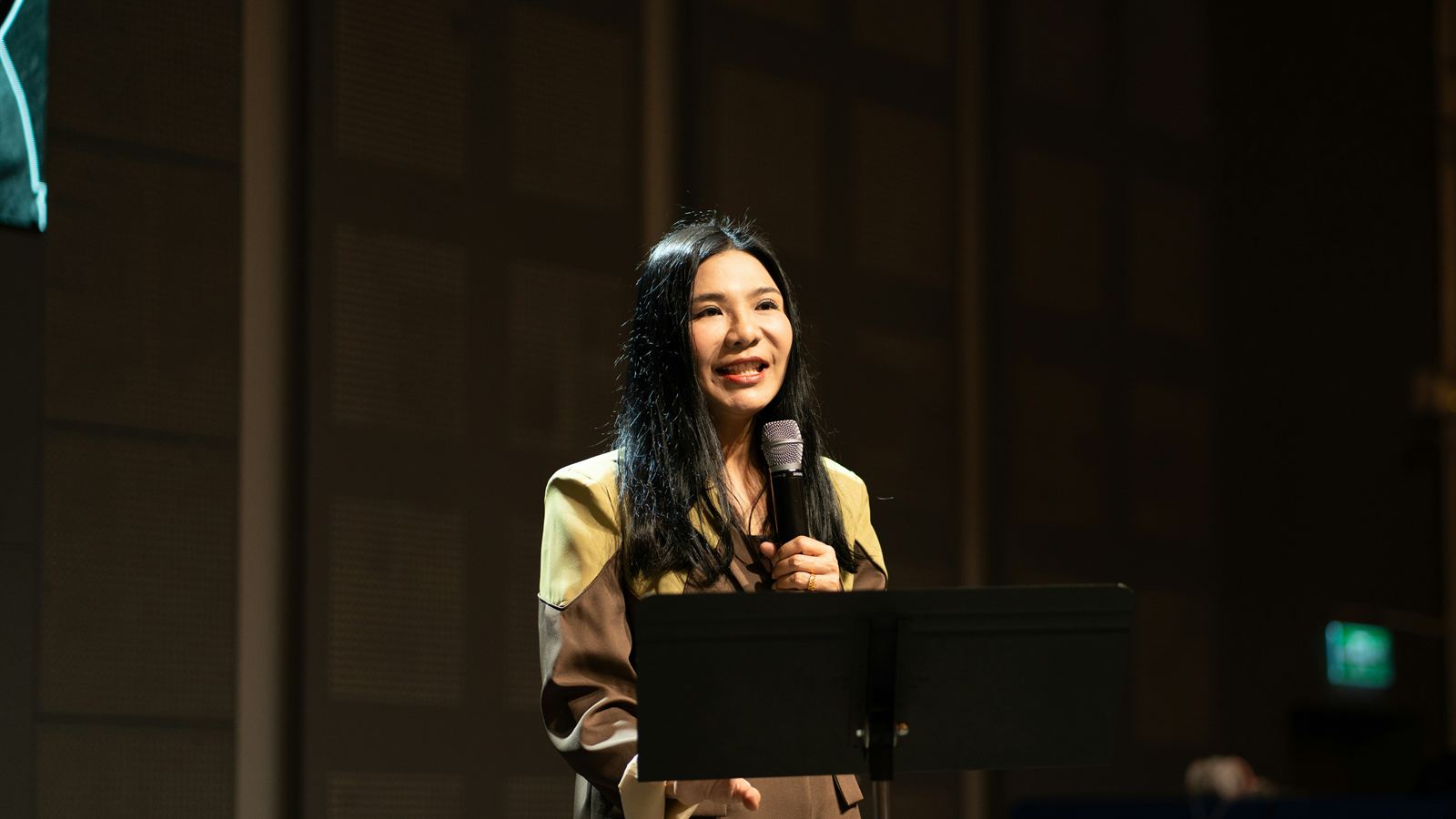 A woman speaking into a microphone on stage